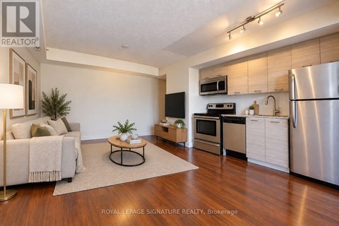 A modern kitchen with stainless steel appliances and a dining area with a white couch and a coffee table.