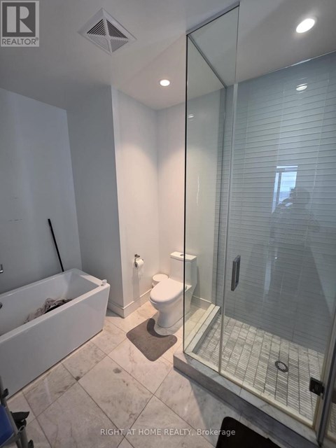 A bathroom with a glass shower door and a white bathtub.