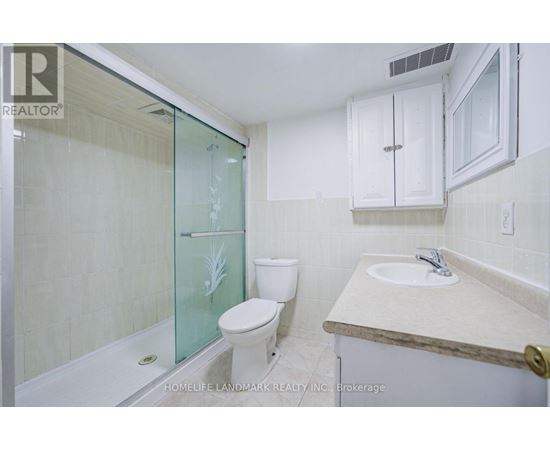 A white toilet sits next to a glass shower door in a bathroom.