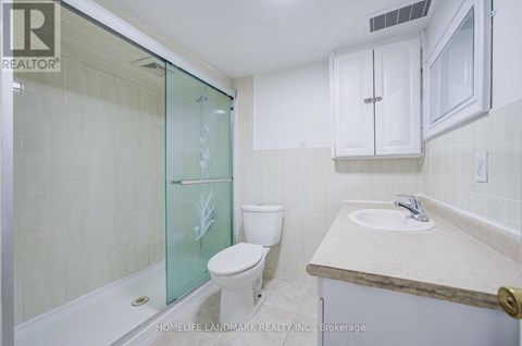 A white toilet sits next to a glass shower door in a bathroom.