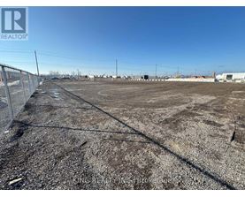A large, empty plot of land with a fence running along the left side.