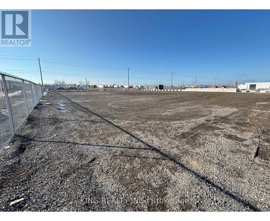 A large, empty plot of land with a fence running along the left side.