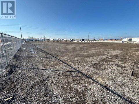 A large, empty plot of land with a fence running along the left side.