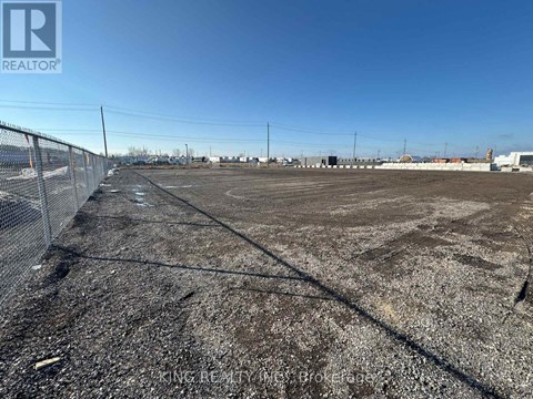 A large, empty plot of land with a fence on the left side.