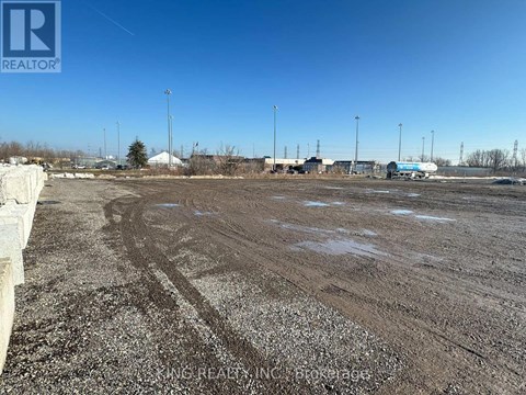 A large, empty field with a clear blue sky above and a building in the distance.