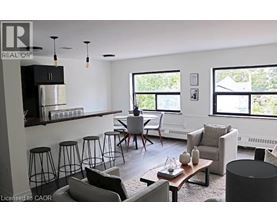 A living room with a black and white color scheme and a kitchen area in the background.