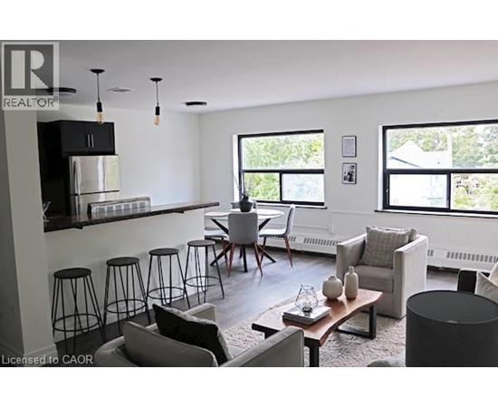A living room with a black and white color scheme and a kitchen area in the background.