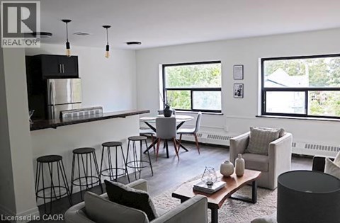 A living room with a black and white color scheme and a kitchen area in the background.