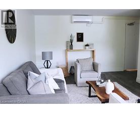A living room with a grey couch, a white chair, and a wooden coffee table.