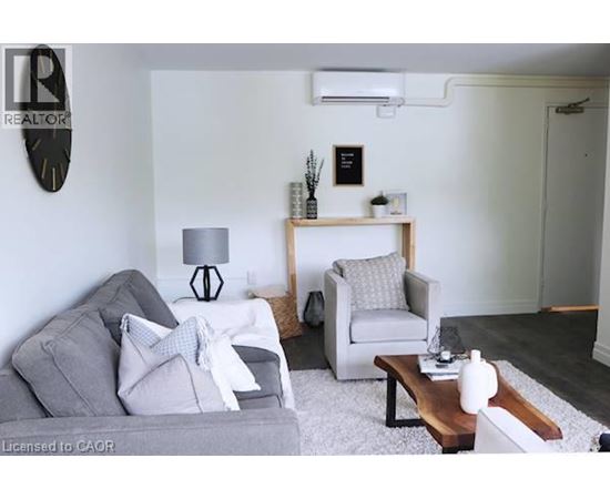 A living room with a grey couch, a white chair, and a wooden coffee table.