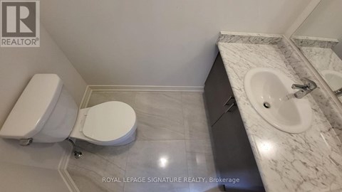 A white toilet and sink in a bathroom.
