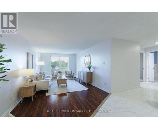 A well-lit, spacious living room with a white couch and a wooden floor.