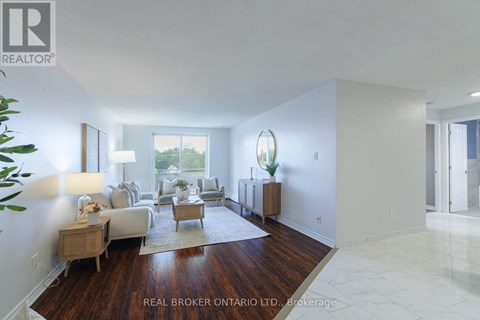 A well-lit, spacious living room with a white couch and a wooden floor.