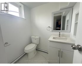 A bathroom with a toilet, sink, and mirror.