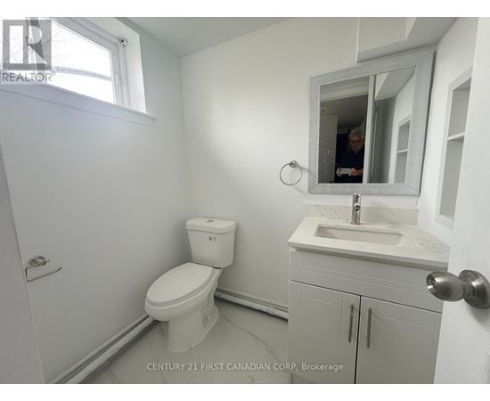 A bathroom with a toilet, sink, and mirror.