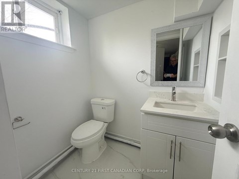 A bathroom with a toilet, sink, and mirror.