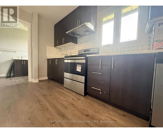 A kitchen with wooden cabinets and a black fridge.