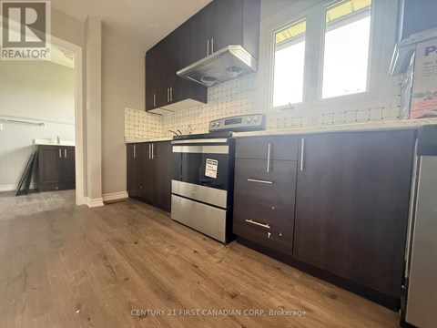 A kitchen with wooden cabinets and a black fridge.