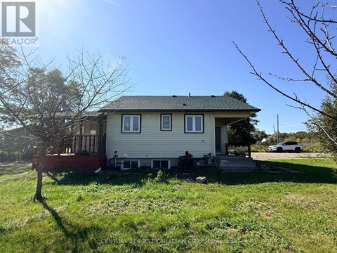 A house with a porch and a tree in front of it.