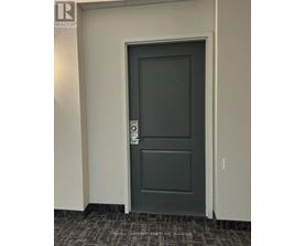 A grey door with a handle and a keypad on the wall.