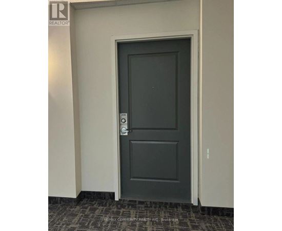 A grey door with a handle and a keypad on the wall.
