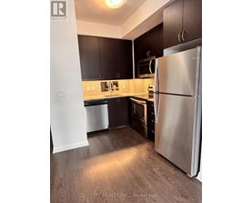 A kitchen with a refrigerator, cabinets, and a microwave.