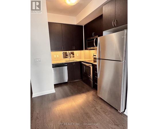 A kitchen with a refrigerator, cabinets, and a microwave.