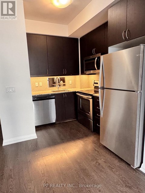 A kitchen with a refrigerator, cabinets, and a microwave.