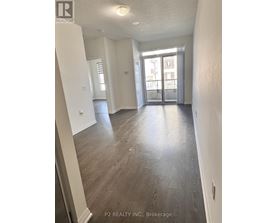 A spacious room with wood flooring and a large window.