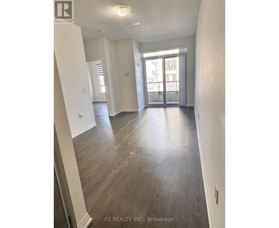 A spacious room with wood flooring and a large window.