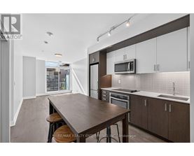 A modern kitchen with a long wooden table and bar stools.