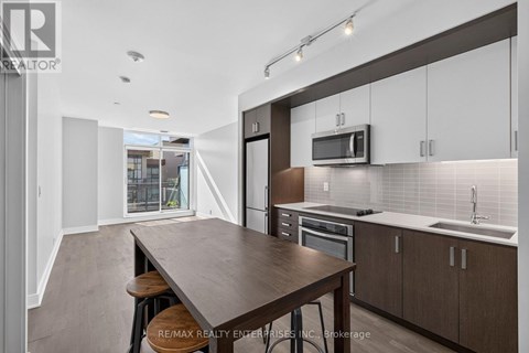 A modern kitchen with a long wooden table and bar stools.