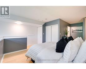 A bedroom with a bed, pillows and a nightstand.