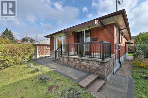 A red brick house with a balcony and a small garden in front.