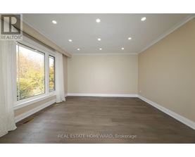 A spacious room with wooden flooring and a large window.