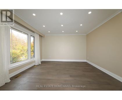 A spacious room with wooden flooring and a large window.