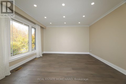 A spacious room with wooden flooring and a large window.