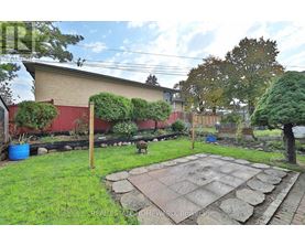 A backyard with a stone patio and a red building in the background.