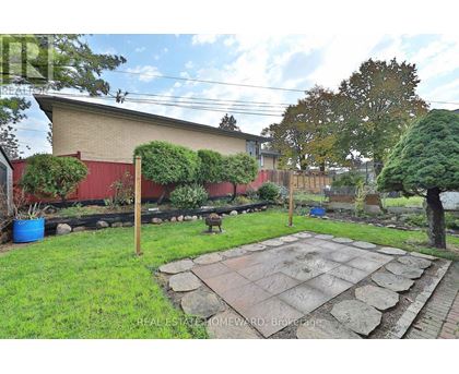 A backyard with a stone patio and a red building in the background.
