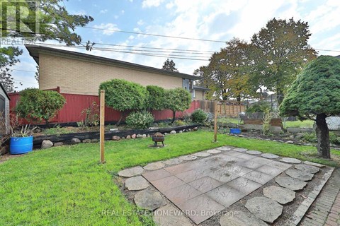 A backyard with a stone patio and a red building in the background.