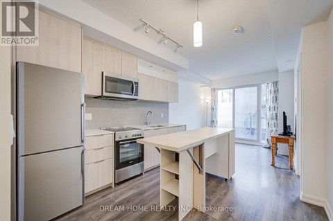 A modern kitchen with a refrigerator, microwave, oven, and sink.