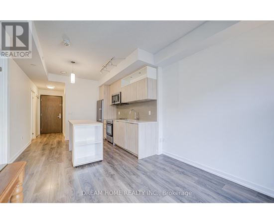 A kitchen with a refrigerator, microwave, and oven in a white cabinetry.