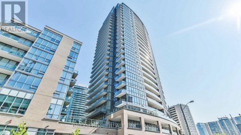 A modern building with a curved glass facade stands tall against a clear sky.