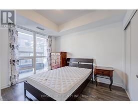 A bedroom with a large bed, a nightstand, and a window with curtains.