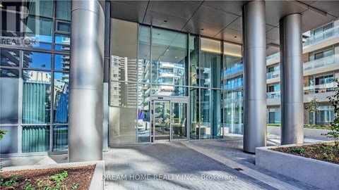 The image shows the front of a building with a glass entrance flanked by four large columns.