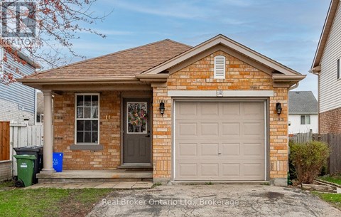 A small brick house with a grey garage door is for sale.