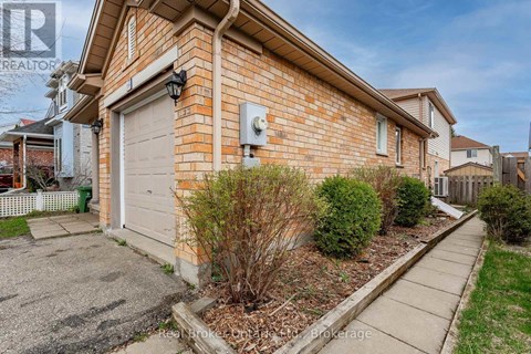 A brick house with a garage door and a small garden in front.