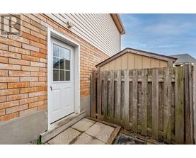 A white door is on a brick wall with a wooden fence in front.