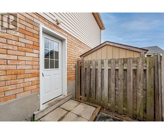 A white door is on a brick wall with a wooden fence in front.