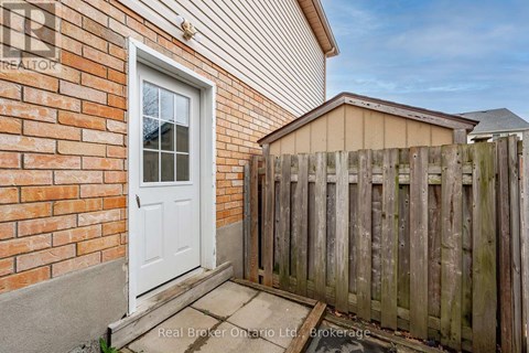 A white door is on a brick wall with a wooden fence in front.